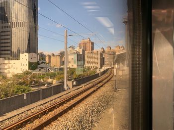 Railroad tracks by buildings in city against sky