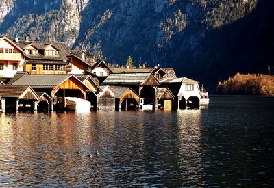 Built structure by lake and buildings against mountain