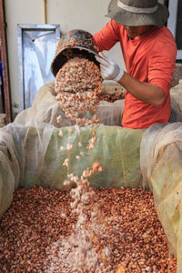 Man poring cocoa beans in container