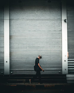 Side view of man walking against wall