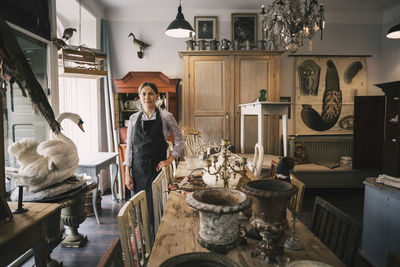 Portrait of smiling female owner standing in antique shop