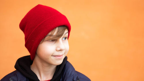 Portrait of boy wearing hat against orange background