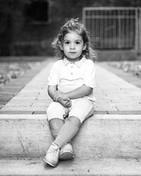 Portrait of girl sitting on footpath