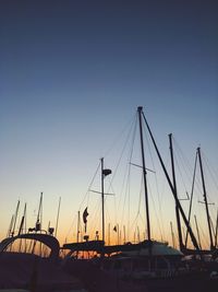 Sailboats moored at harbor against clear sky during sunset