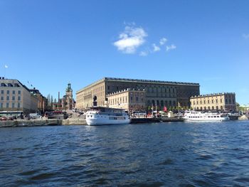 View of buildings by sea against blue sky