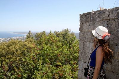 Woman leaning on wall against sky at rhodes