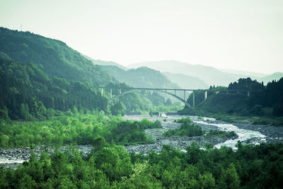 Scenic view of river by mountains against sky