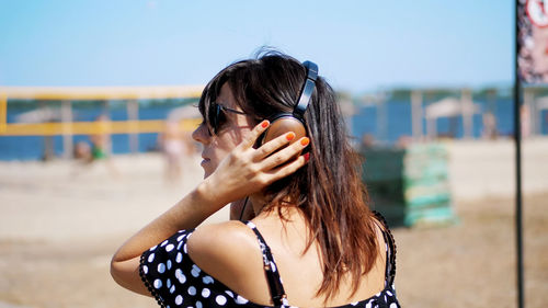 Portrait, beautiful girl in sun glasses wearing big black headphones, listening to music from