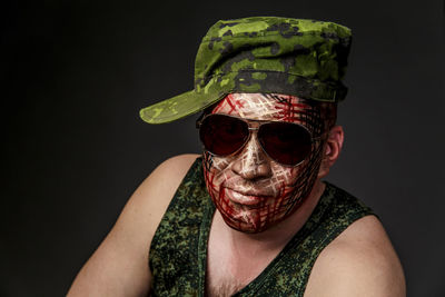 Portrait of soldier with camouflage make-up against black background