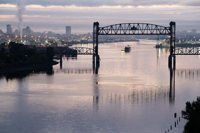 Bridge over river against sky in city