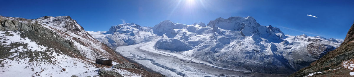 Panoramic view of snowcapped mountains against clear blue sky