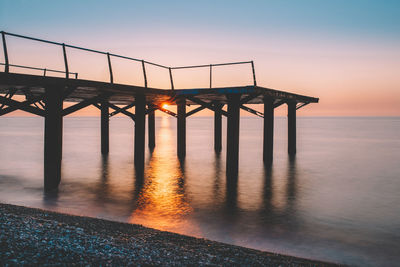 Bridge over sea against sky during sunset