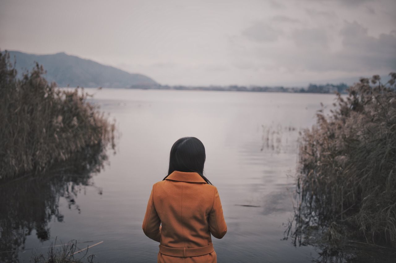 water, rear view, one person, real people, nature, lake, leisure activity, beauty in nature, lifestyles, sky, standing, scenics - nature, non-urban scene, plant, day, tranquility, tranquil scene, three quarter length, outdoors, looking at view, warm clothing