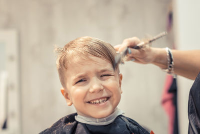 Cropped image of barber cutting hair of boy at shop