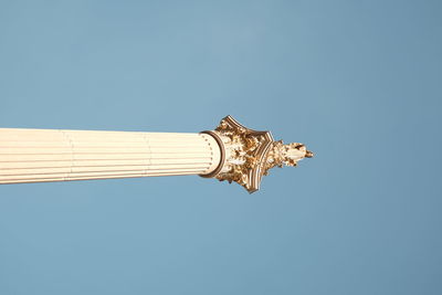Low angle view of cross against building against clear blue sky