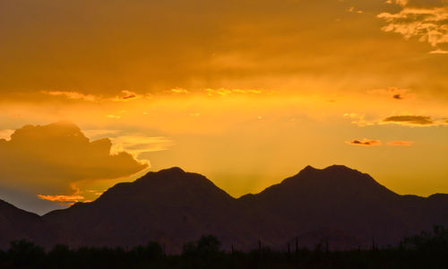 Scenic view of silhouette mountains against orange sky