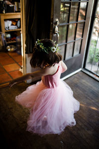 Young girl spinning by front door wearing tutu and flower crown