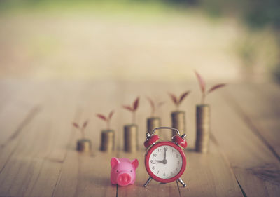 Stacked coins with piggy bank and alarm clock on table