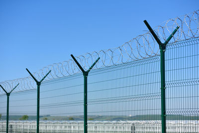 Barbed wire fence against clear blue sky