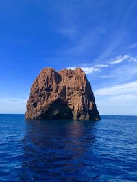 Rock formation in sea against blue sky