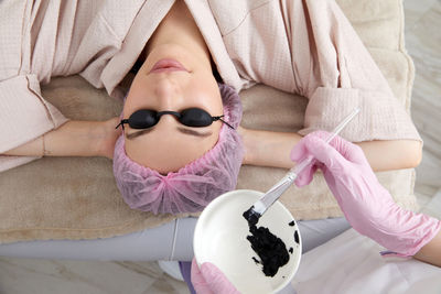 Portrait of young woman holding dentures while sitting on bed at home