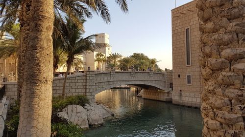 Bridge over canal by buildings against sky