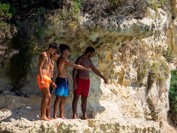 Full length of friends standing on rock