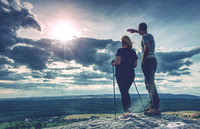 Rear view of man standing on mountain against sky