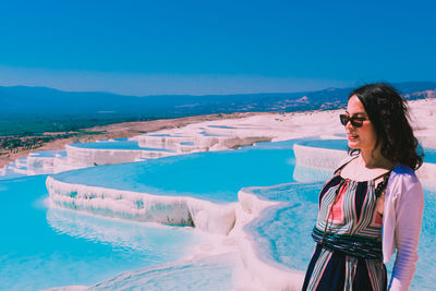 Woman looking at swimming pool against blue sky