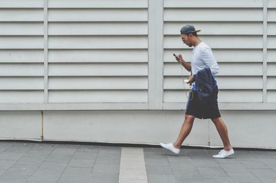 Side view of young man standing against wall
