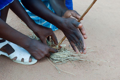 High angle view of men burning fire with stick and grass