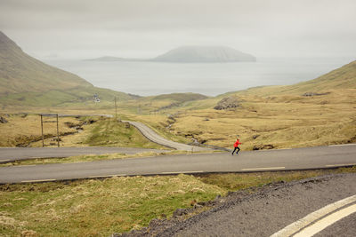 Man riding motorcycle on road against sky