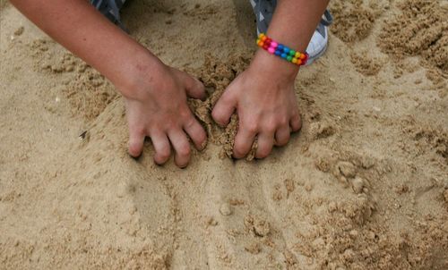 Low section of boy playing on sand at beach