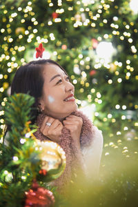 Portrait of young woman standing by christmas tree