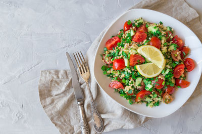 Tabbouleh salad on a dish on light gray concrete background. lebanese cuisine. top view.