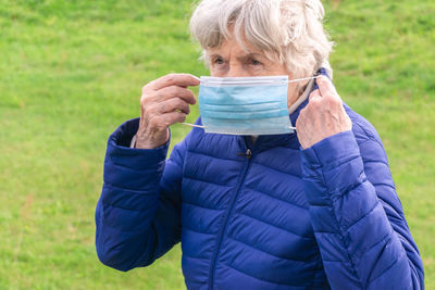 Close-up of senior woman wearing mask standing outdoors