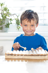 Portrait of smiling boy playing xylophone on table