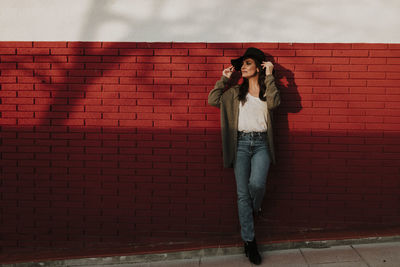 Portrait of woman standing against brick wall