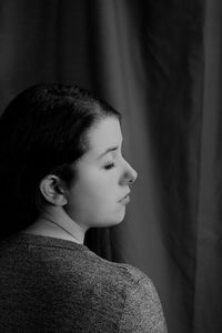 Young woman with closed eyes standing indoors