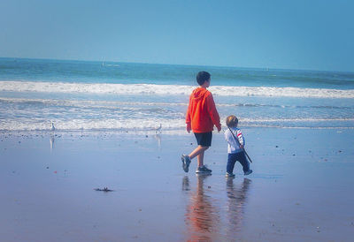 Rear view of father and son on beach