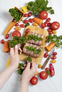 Female hands decorate with parsley minced meat sausages in bacon with green