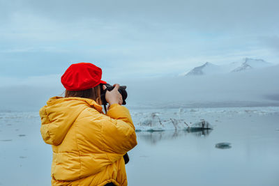 Rear view of person photographing against sky