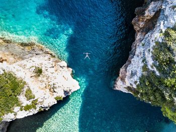 Aerial view of woman swimming in sea by rock formations