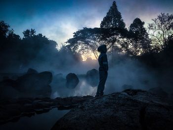Man standing on rock against sky