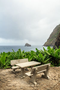 Chair on beach against sky