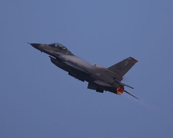 Low angle view of airplane flying against clear blue sky