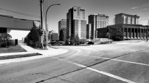 City street by modern buildings against sky