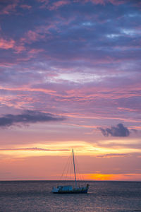 Sailboat sailing on sea against sky during sunset