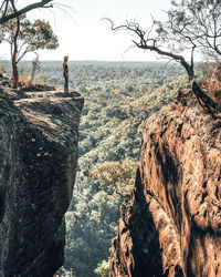 Girl standing on cliff by mountain against sky