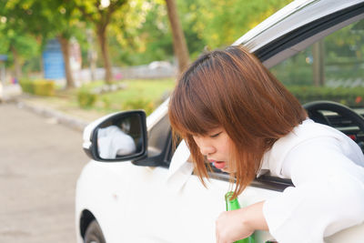 Portrait of young woman holding umbrella while sitting in car